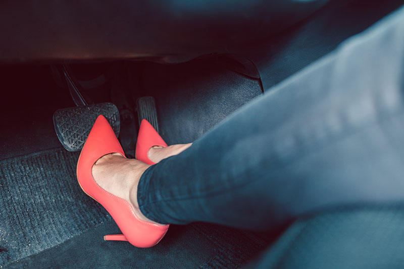 Frau mit High Heels am Gaspedal