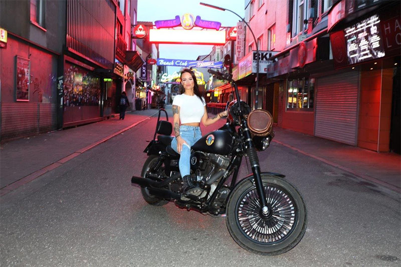 Cheeky Cate sitzt auf einem Motorrad in der Reeperbahn