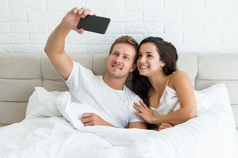 Mann und Frau machen Selfie im Bett